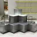 Metal display cubes arranged in a room with glass shelves in the background.