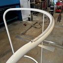 White metal frame in a workshop setting with tools and equipment in the background