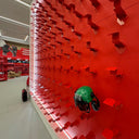 Red ceiling with geometric design and a person wearing a green helmet underneath.