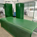 Green metal bench with glass panels in an indoor setting