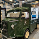 Green vintage-style pizza truck inside a warehouse.