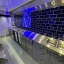 Modern kitchen with stainless steel counters and blue tiled wall