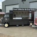 Coffee truck with 'Great Coffee for the Great Outdoors' sign in front of a building.