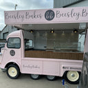 Pink food truck with 'Beesley Bakes' branding parked outside a building.