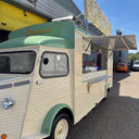 Vintage-style food truck with 'Gourmets' branding parked on a street.