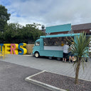 Blue food truck with 'Hunters' sign in colorful letters outdoors