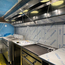 Commercial kitchen under construction with stainless steel appliances and blue protective covering on walls.