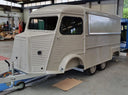 Beige food truck on a trailer inside a warehouse.