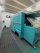 Turquoise trailer inside a car wash with 'Cater' branding on the wall.